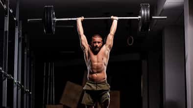 Ein Mann mit einer Langhantel über dem Kopf beim Schulterdrücken