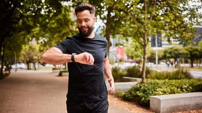 Ein Mann geht joggen und schaut dabei auf seinen Fitness-Tracker