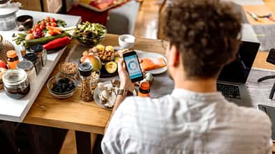 Ein Mann sitzt an einem Esstisch und trackt sein Essen