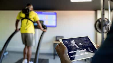 Fitness instructor using a tablet while performing a physical test at a health club