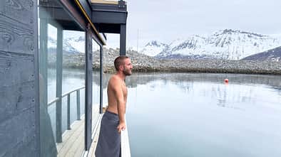 Man relaxing on sauna dock and contemplating the fjord view