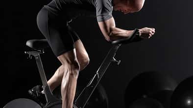 Man cycling on exercise bike, side view