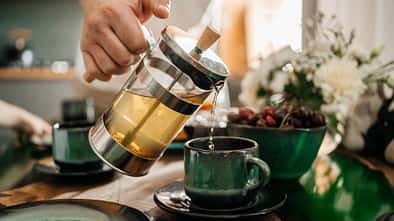 man pouring tea into a cup, close-up