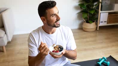 Young man eating healthy breakfast at home after fitness training
