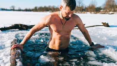 Courageous man taking an ice bath in frozen lake during winter