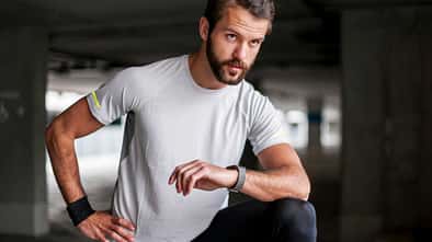 Mann macht eine Trainingspause und blickt auf seine Smartwatch.