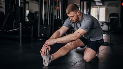 Mann dehnt seine Beinmuskulatur nach dem Training im Fitnessstudio.