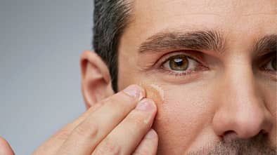 Closeup: Mann trägt Creme im Gesicht auf 