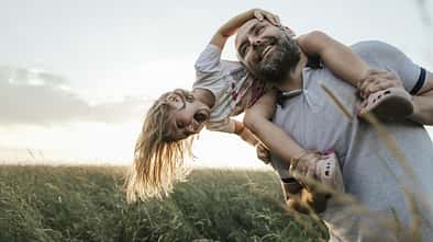 Ein Vater trägt seine Tochter auf seinen Schultern