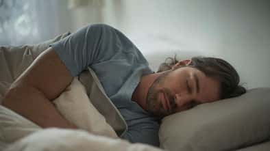 Ein junger Mann schläft zugedeckt in einem Bett