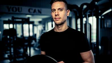 Ein junger Mann hält Gewichte im Gym
