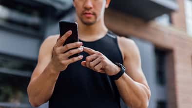 Ein Mann in Sportkleidung schaut auf sein Smartphone Ein Mann in Sportkleidung schaut auf sein Smartphone