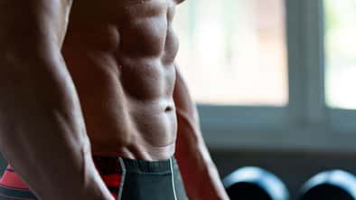 Die seitliche Ansicht von dem Sixpack eines trainierten Mannes im Gym