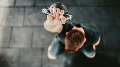 Junger Mann hält eine Kettlebell über seinem Kopf