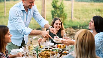 Lächelnde Freunde, die ein Mittagessen im Freien in einer mediterranen Umgebung genießen