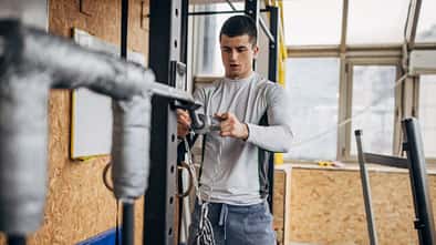 Ein junger Mann bereitet im Fitnessstudio Ketten für sein Training vor