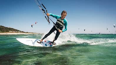 Mann beim Kitesurfen auf dem Meer, im Hintergrund sind viele weitere Kitesurfer