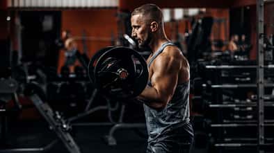 Muskulöser Mann im Fitnessstudio beim Langhantelheben