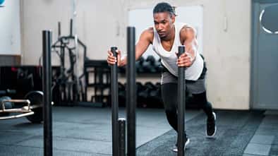 Sportler schiebt einen gewichteten Schlitten in einem Fitnessstudio