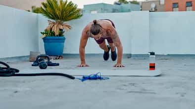 Ein Mann macht draußen oberkörperfrei Burpees 