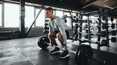 Ein Mann führt Deadlifts aus mit einer Langhantel im Gym