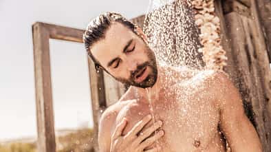 Ein junger Mann nimmt draußen eine kalte Dusche