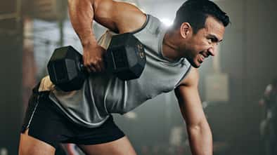Ein trainierter Mann macht Rudern im Gym mit einer Kurzhantel