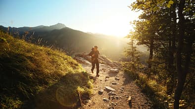Ein Mann wandert in einer sonnigen Berglandschaft.