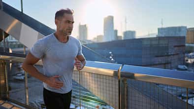 Mann joggt über eine Brücke mit einer Stadt im Hintergrund
