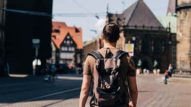 Ein junger Mann mit Rucksack spaziert durch die Straßen einer Altstadt
