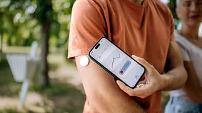 Ein Mann überprüft seinen Blutzucker mit einem Smartphone