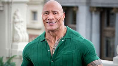 Dwayne Johnson lächelt im grünen Oberteil in die Kamera