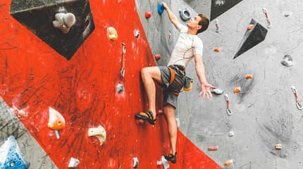Bouldern Mann greift beim Bouldern zu
