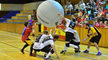 Eine Gruppe Männer spielt in einer Sporthalle mit einem großen Ball, der in die Luft geschlagen wird. Eine Gruppe Männer spielt in einer Sporthalle mit einem großen Ball, der in die Luft geschlagen wird.