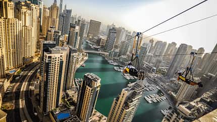 Zwei Personen hängen an einer Zipline über dem Hafen von Dubai Zwei Personen hängen an einer Zipline über dem Hafen von Dubai