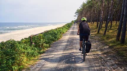Ein junger Mann fährt Fahrrad am Strand
