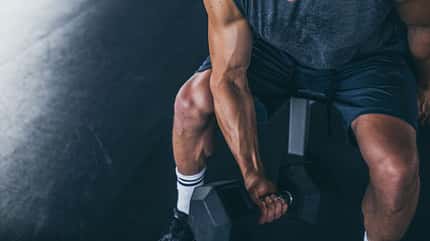 Sportlicher Mann trainiert mit einer Kurzhantel Sportlicher Mann trainiert mit einer Kurzhantel