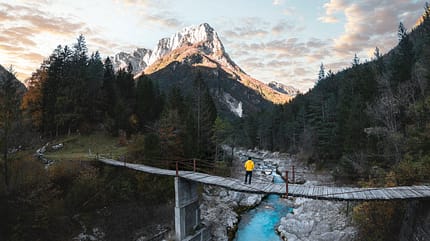 Man standing on a suspension bridge above a mountain river Man standing on a suspension bridge above a mountain river