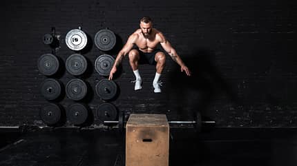 Young strong fit sweaty muscular man with big muscles doing box jump workout in the gym as hardcore cross training Young strong fit sweaty muscular man with big muscles doing box jump workout in the gym as hardcore cross training