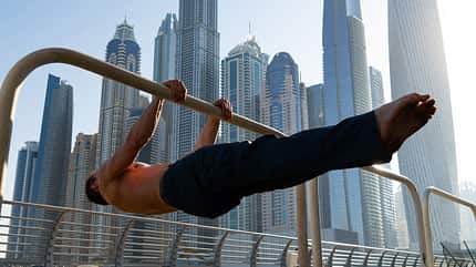 Muscular man doing workout on the street with cityscape of skyscrapers on background in Dubai. Concept of healthy lifestyle and modern Muscular man doing workout on the street with cityscape of skyscrapers on background in Dubai. Concept of healthy lifestyle and modern