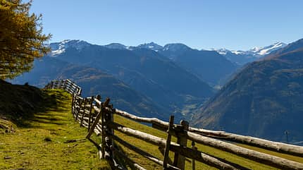 Wooden fence on mountain meadow, in the background South Tyrolean mountains, Naturns, South Tyrol, Italy Wooden fence on mountain meadow, in the background South Tyrolean mountains, Naturns, South Tyrol, Italy
