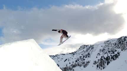 Junger Mann springt auf dem Snowboard im Schnee Junger Mann springt auf dem Snowboard im Schnee