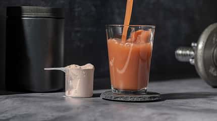 Schokoladen Proteinshake wird in ein Glas geschüttet Schokoladen Proteinshake wird in ein Glas geschüttet
