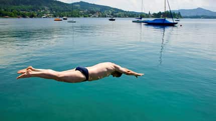 Mann macht einen Kopfsprung in den Wörthersee, Österreich Mann macht einen Kopfsprung in den Wörthersee, Österreich