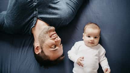 Father playing in bed with his little baby boy Father playing in bed with his little baby boy