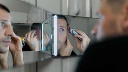 Mann verwendet Elektrorasierer zum Haare schneiden