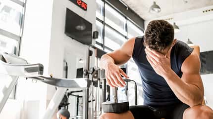 Tired,Man,With,Dumbbell,Having,Break,In,Gym