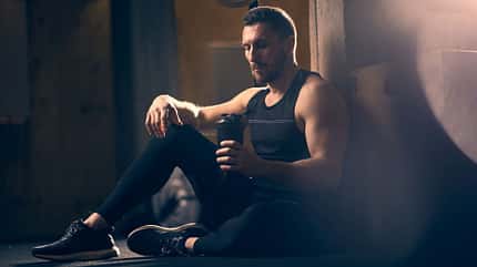 Mann sitzt im Gym mit einem Shaker und macht Pause Mann sitzt im Gym mit einem Shaker und macht Pause