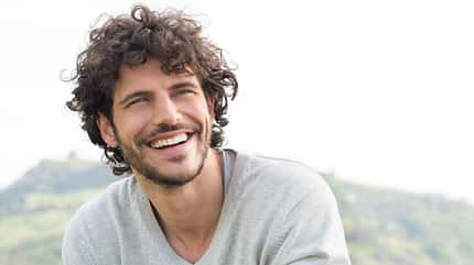 Mann mit Locken lacht in Kamera Mann mit Locken lacht in Kamera