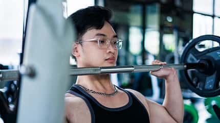 muscular,strength,physique,fitness goals,fitness routine,motivat A,Young,Man,With,Glasses,Engages,In,A,Barbell,Shoulder